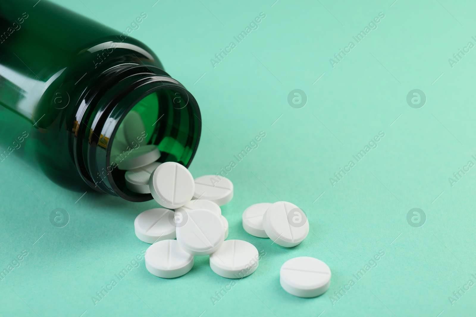 Photo of Medical bottle with antibiotic pills on turquoise background, closeup. Space for text