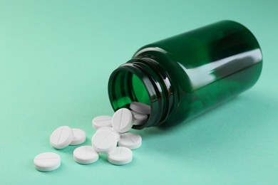 Photo of Medical bottle with antibiotic pills on turquoise background, closeup