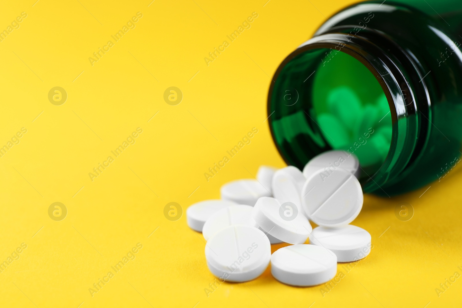 Photo of Medical bottle with antibiotic pills on yellow background, closeup. Space for text