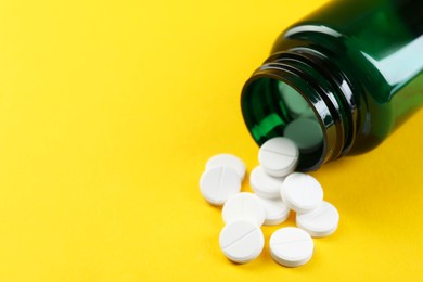 Photo of Medical bottle with antibiotic pills on yellow background, closeup. Space for text