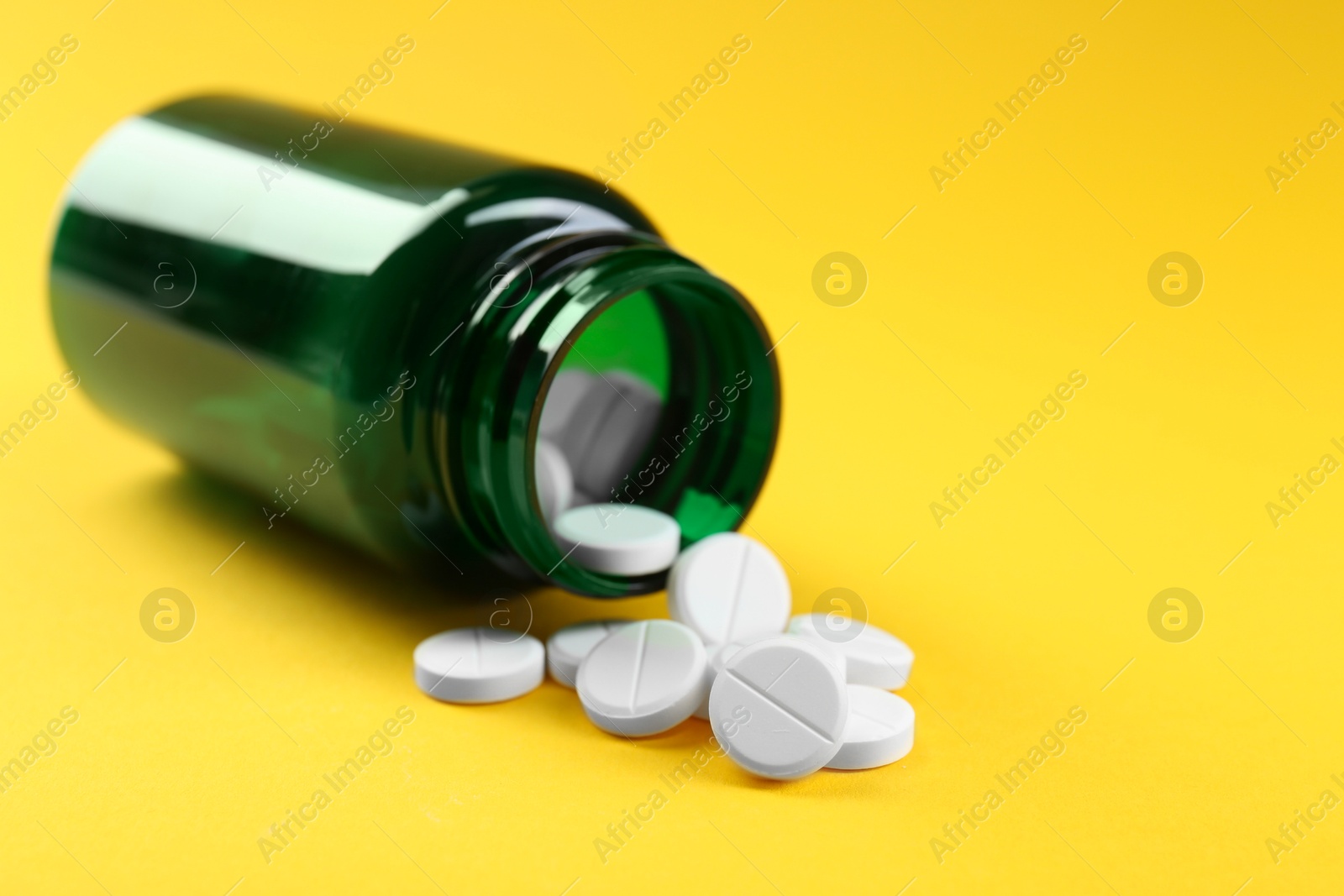 Photo of Medical bottle with antibiotic pills on yellow background, closeup