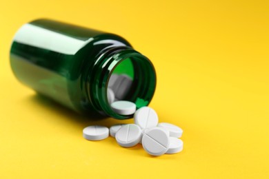 Photo of Medical bottle with antibiotic pills on yellow background, closeup