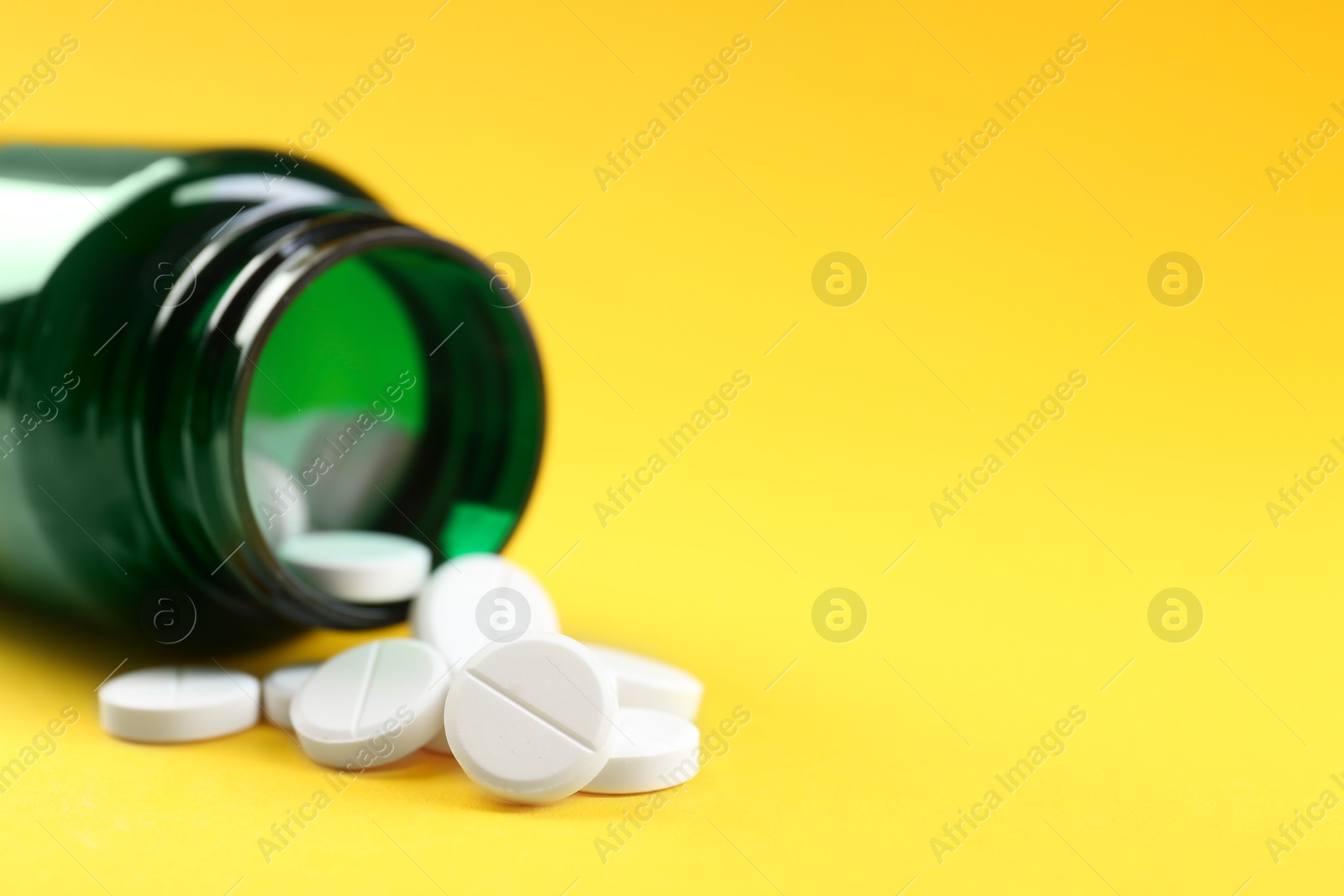 Photo of Medical bottle with antibiotic pills on yellow background, closeup. Space for text