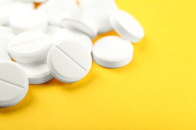 Photo of Pile of antibiotic pills on yellow background, closeup