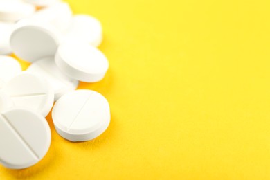 Photo of Pile of antibiotic pills on yellow background, closeup. Space for text