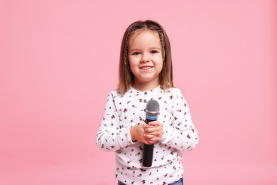 Photo of Smiling girl with microphone on pink background