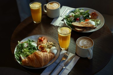 Photo of Tasty breakfast. Different meals and drinks served on wooden table in cafe, closeup