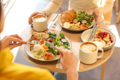 Photo of Women having tasty breakfast in cafe, closeup