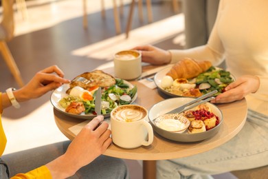 Photo of Women having tasty breakfast in cafe, closeup