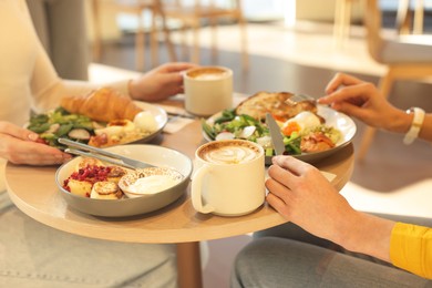 Photo of Women having tasty breakfast in cafe, closeup