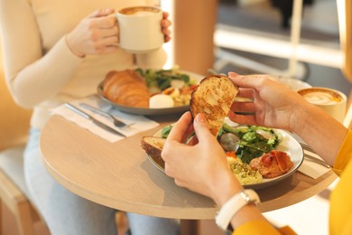 Photo of Women having tasty breakfast in cafe, closeup