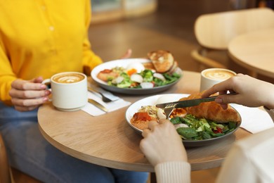 Photo of Women having tasty breakfast in cafe, closeup