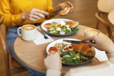 Photo of Women having tasty breakfast in cafe, closeup