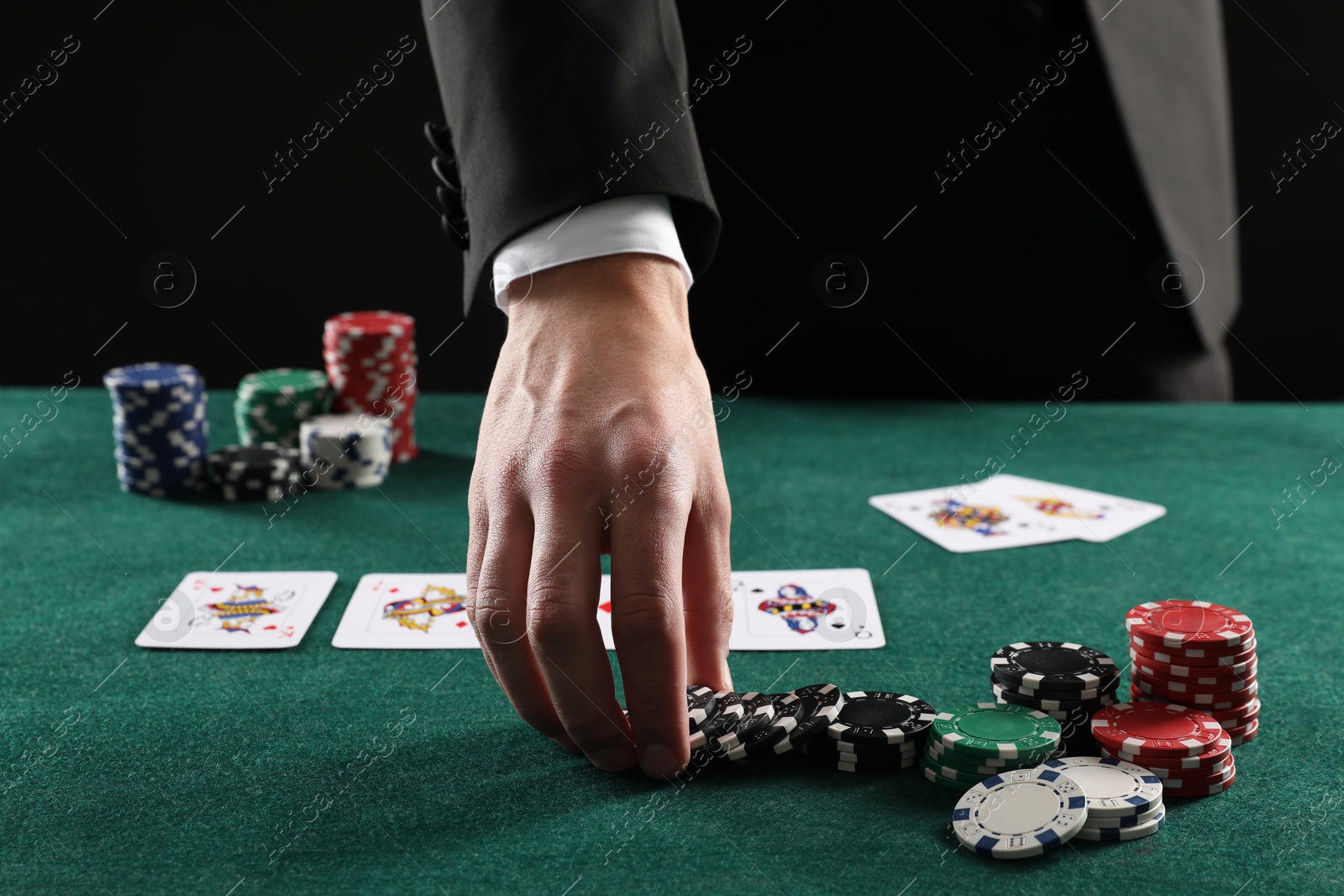 Photo of Man with cards and casino chips playing poker at gambling table, closeup