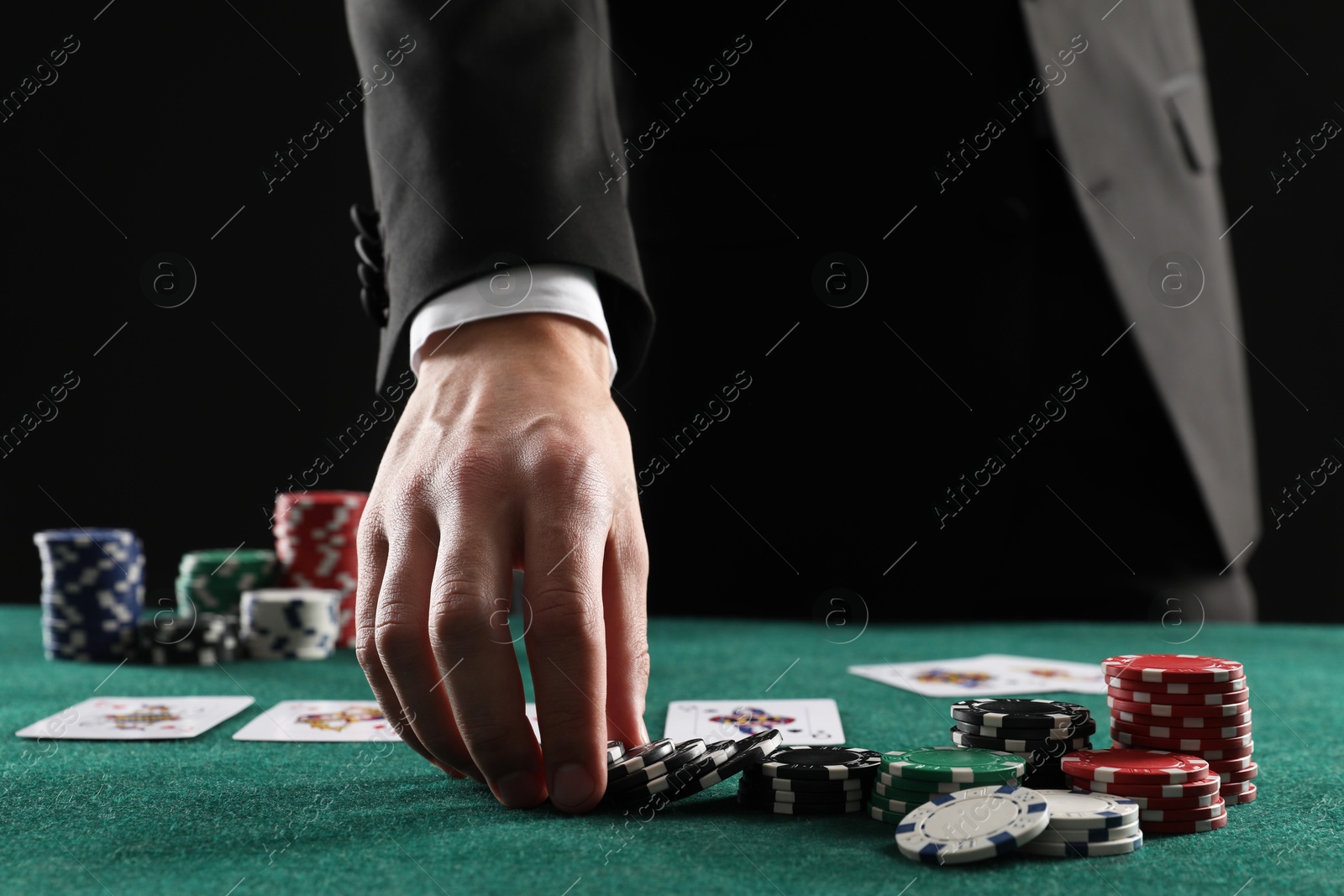 Photo of Man with cards and casino chips playing poker at gambling table, closeup