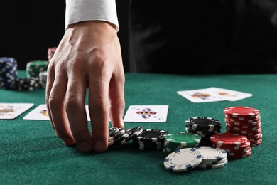 Photo of Man with cards and casino chips playing poker at gambling table, closeup