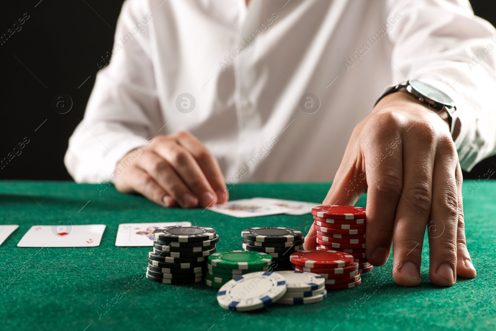 Photo of Man with cards and casino chips playing poker at gambling table, closeup