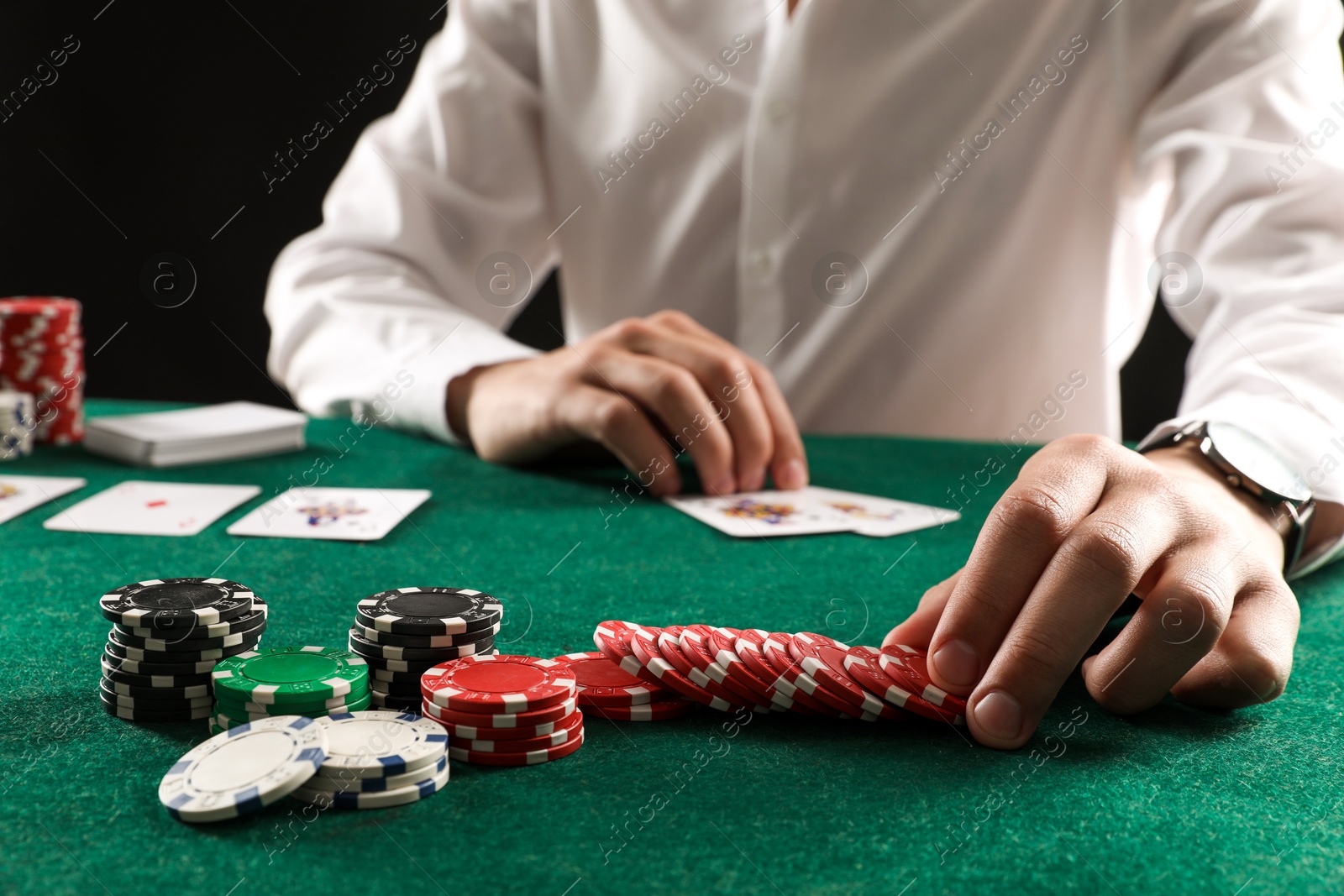 Photo of Man with cards and casino chips playing poker at gambling table, closeup