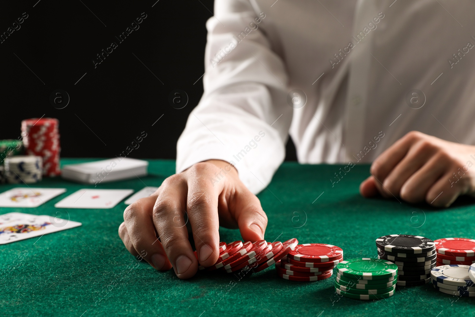 Photo of Man with cards and casino chips playing poker at gambling table, closeup