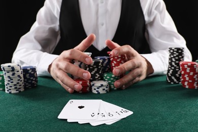 Photo of Man with cards and casino chips playing poker at gambling table, closeup