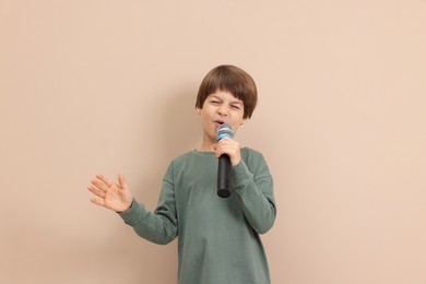 Photo of Cute boy with microphone singing near beige wall