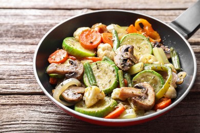 Photo of Different vegetables and mushrooms in frying pan on wooden table, closeup