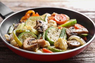 Photo of Different vegetables and mushrooms in frying pan on wooden table, closeup