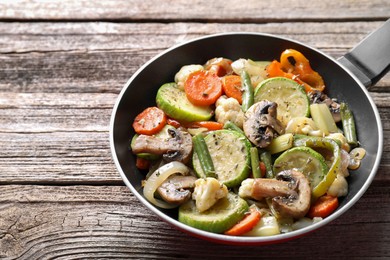 Photo of Different vegetables and mushrooms in frying pan on wooden table, closeup