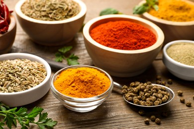 Photo of Different aromatic spices on wooden table, closeup