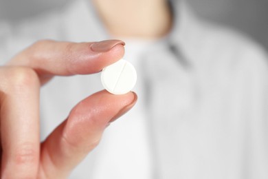 Photo of Woman holding antibiotic pill, closeup. Selective focus