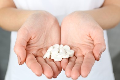 Photo of Woman holding many antibiotic pills, closeup view