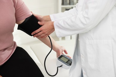 Photo of Nutritionist measuring overweight woman's blood pressure in hospital, closeup