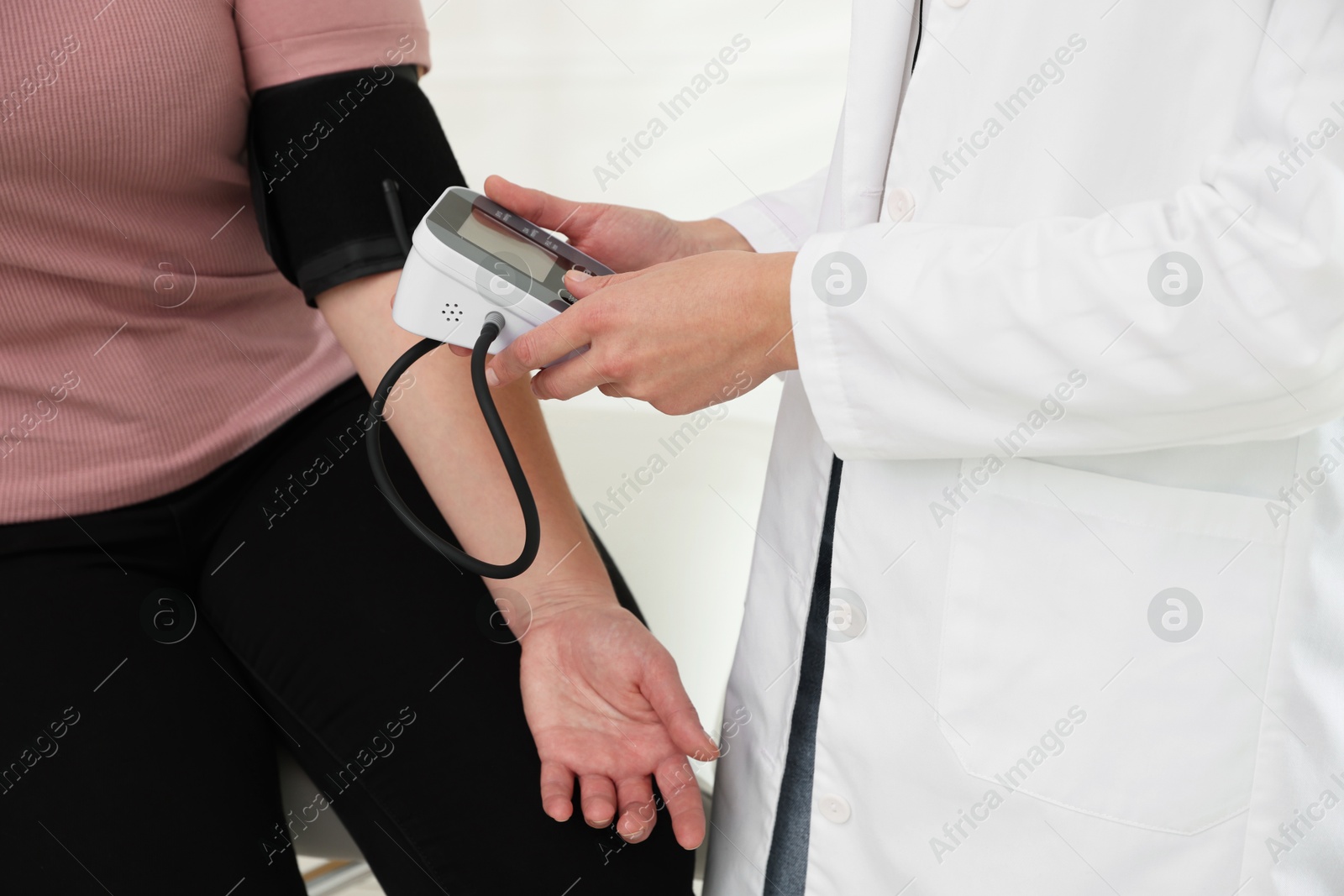 Photo of Nutritionist measuring overweight woman's blood pressure in hospital, closeup