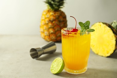 Photo of Tasty pineapple cocktail with mint and cherry in glass served on light table