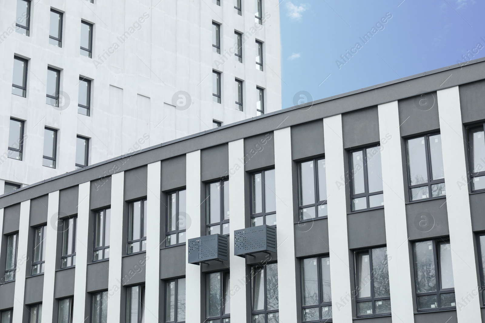 Photo of Modern buildings with many windows against blue sky