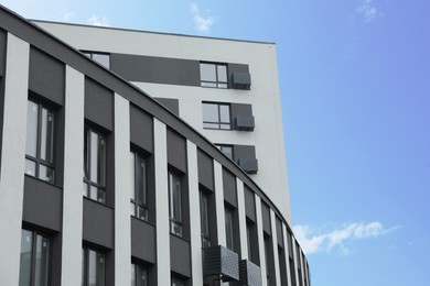 Photo of Modern buildings with many windows against blue sky, low angle view. Space for text