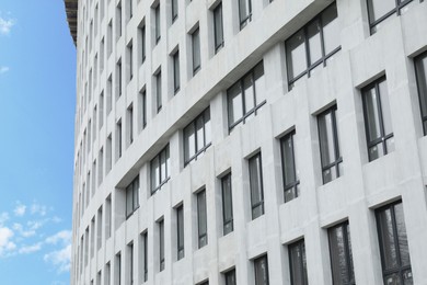 Photo of Modern building with many windows against blue sky, low angle view