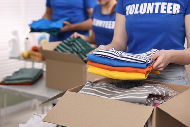 Photo of Volunteers putting clothes into donation boxes at indoors, closeup