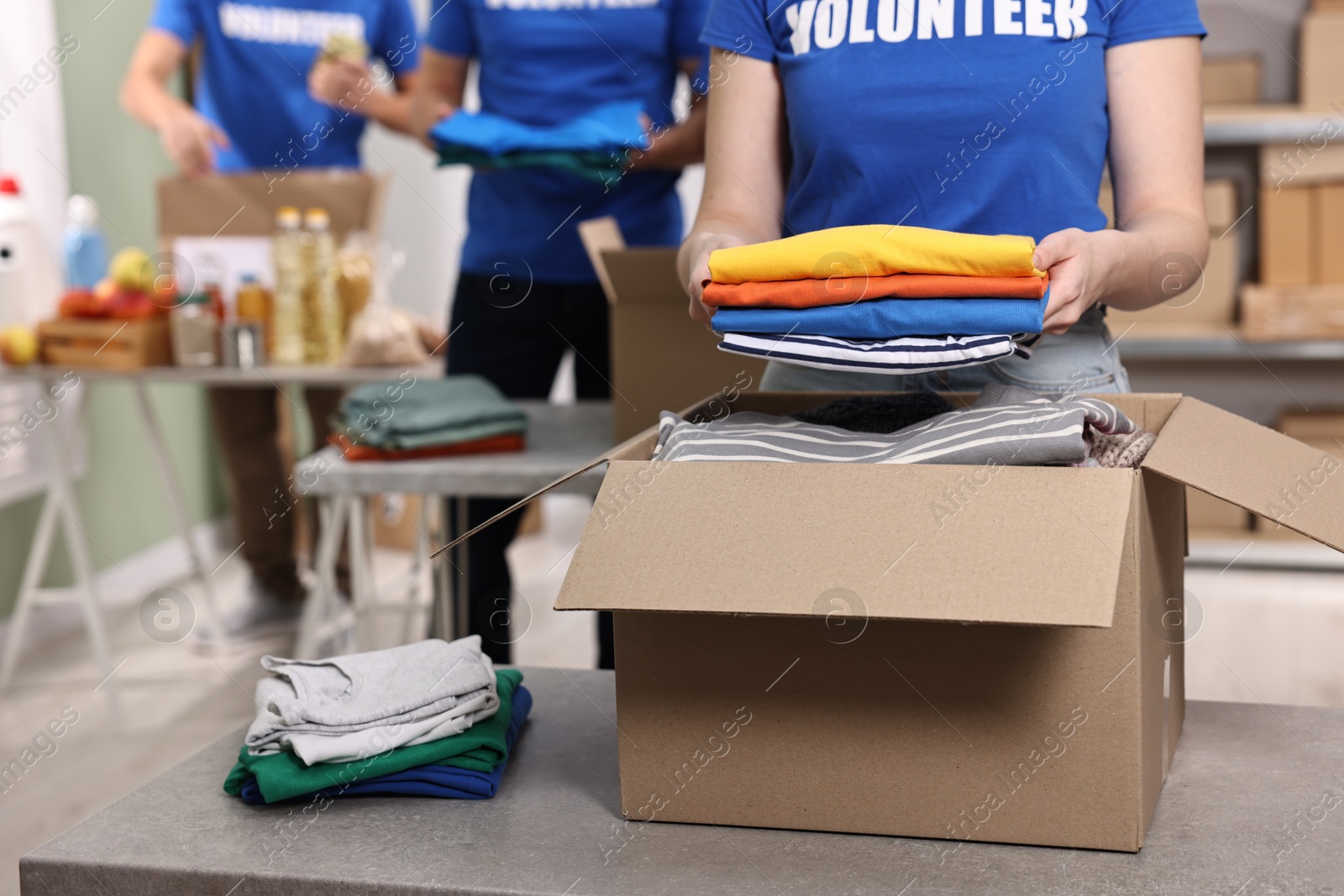 Photo of Volunteers packing donation goods at tables indoors, closeup