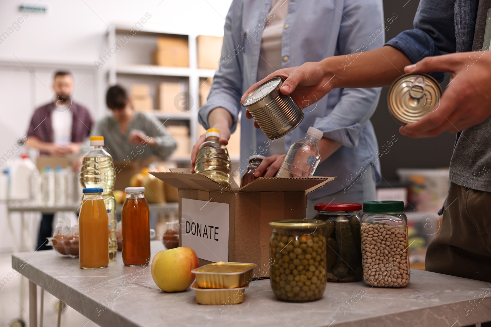 Photo of Volunteers packing food donations at table indoors, closeup