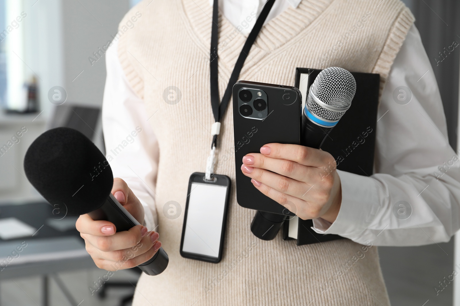 Photo of Journalist with microphones, smartphone and notebook indoors, closeup