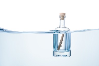 Photo of Corked glass bottle with rolled letter in water on white background