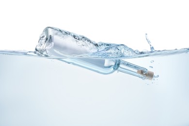 Photo of Corked glass bottle with rolled letter in water on white background