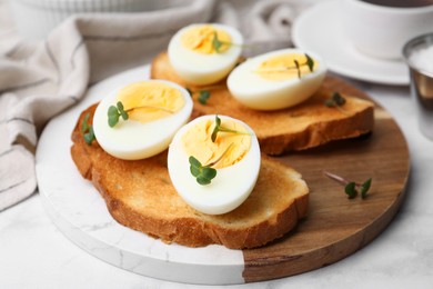 Photo of Sandwiches with hard boiled eggs on white marble table, closeup