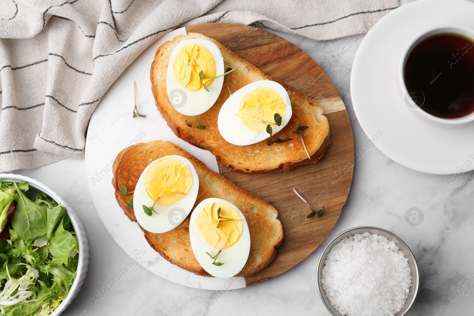 Photo of Sandwiches with hard boiled eggs and tea on white marble table, flat lay