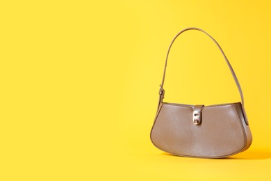 Photo of Stylish brown leather bag on yellow background