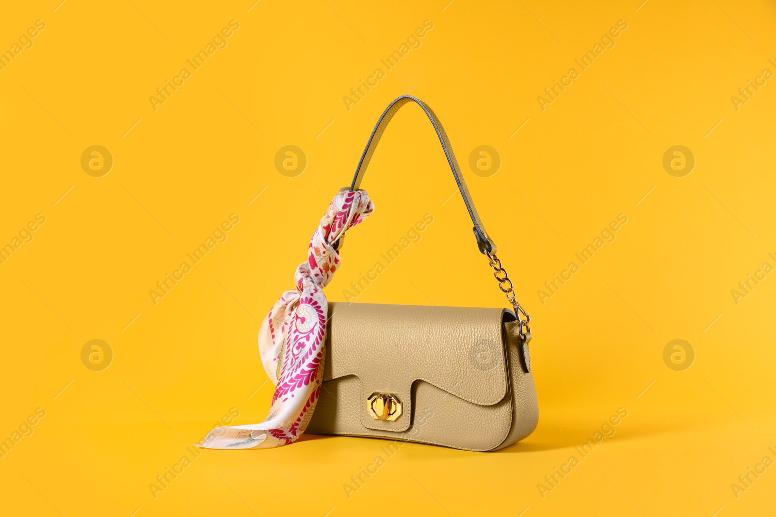 Photo of Stylish leather bag with handkerchief on yellow background