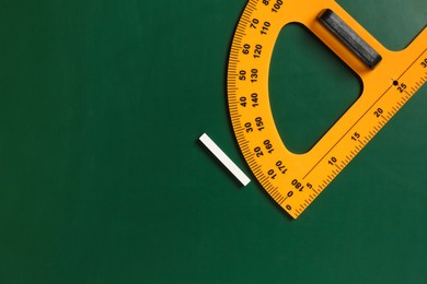 Photo of Protractor ruler and chalk on green chalkboard, top view. Space for text