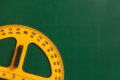 Photo of Protractor ruler on green chalkboard, top view. Space for text