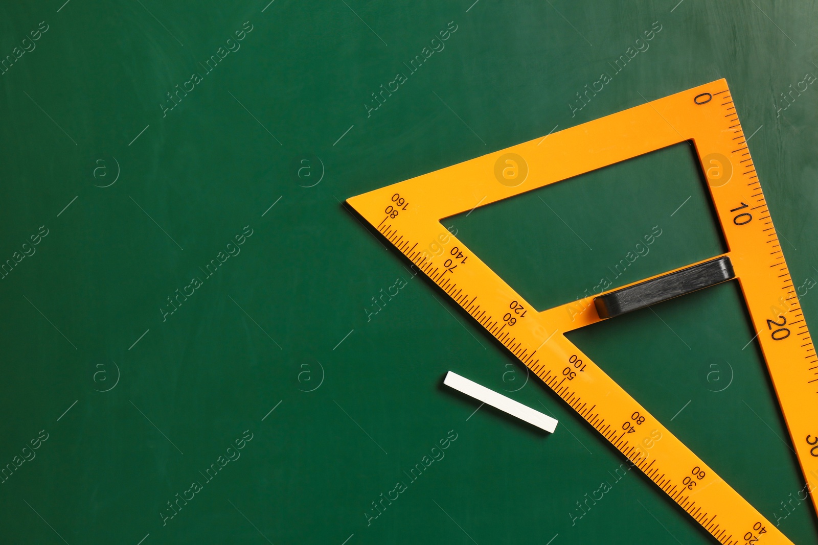 Photo of Triangle ruler and chalk on green chalkboard, top view. Space for text